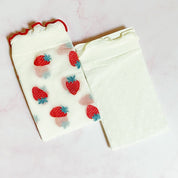 pair of socks. one strawberry pattern. one white with dots. soft, stretchy material. sheer pattern.