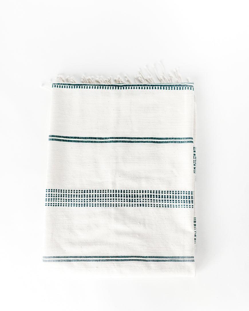 Ethically crafted in Ethiopia. Cotton throw blanket. Measures 38 x 72 inches. natural with navy.